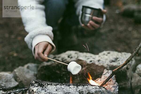Frau brennt Marshmallows am Lagerfeuer