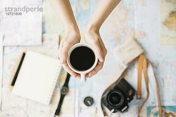 Draufsicht Person s Hand hält Kaffeetasse verschwommen Weltreisekarte