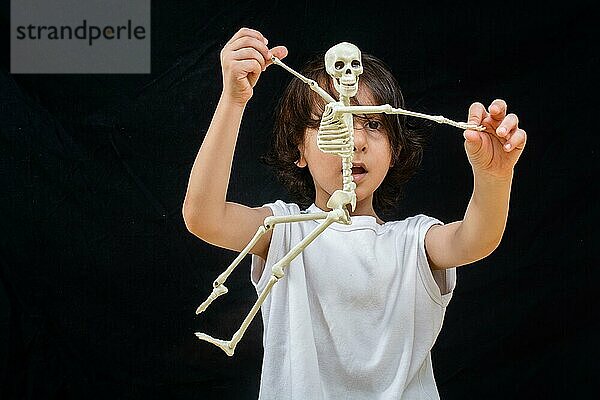 Kleiner Junge hält ein kleines künstliches Skelett in der Hand