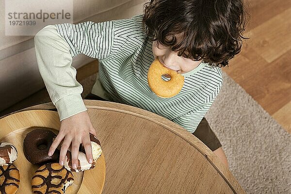 Kind ißt Doughnuts zu Hause