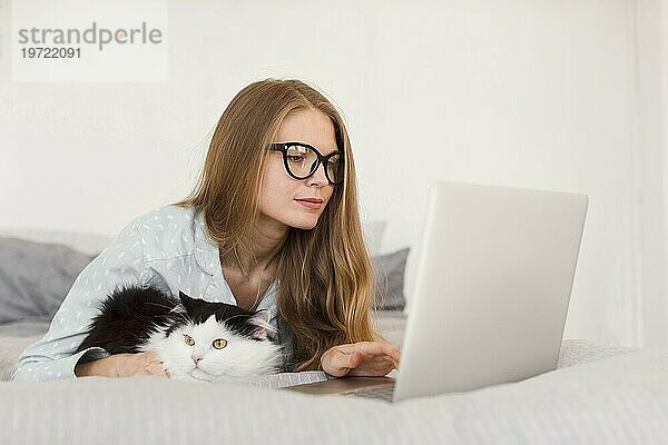 Seitenansicht Frau arbeitet Laptop von zu Hause Pyjamas mit Katze