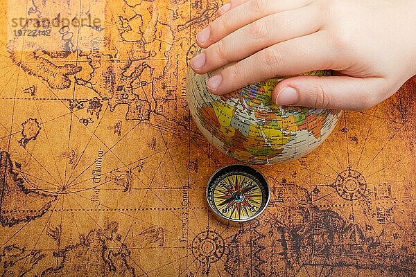 Kompass auf Karte neben einem Globus in der Hand