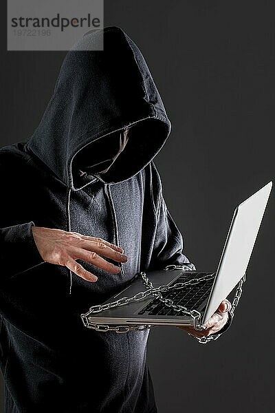 Seitenansicht eines männlichen Hackers mit einem durch eine Metallkette geschützten Laptop