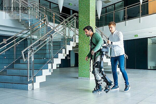 Mechanisches Exoskelett  Physiotherapeut  der mit einer behinderten Person mit Roboterskelett geht  Physiotherapie in einem modernen Krankenhaus: