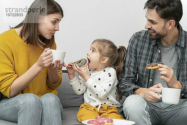 Junges Paar mit Kind ißt Donuts