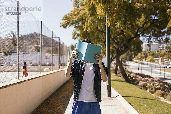 Teenager schließt Gesicht mit Buch
