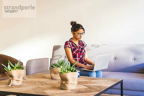 Horizontales Foto mit Kopierbereich einer jungen Frau  die von zu Hause aus mit einem Laptop arbeitet