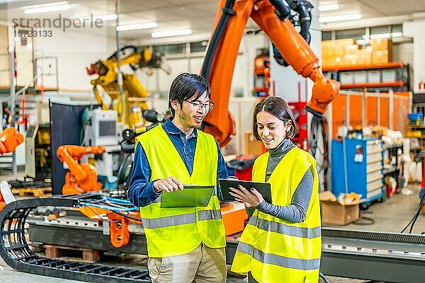 Ingenieure verwenden ein digitales Tablet zur Steuerung der Produktion einer Roboterarmfabrik