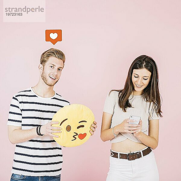 Wie Symbol Mann hält Kuss Emoji in der Nähe ihrer Freundin mit Smartphone