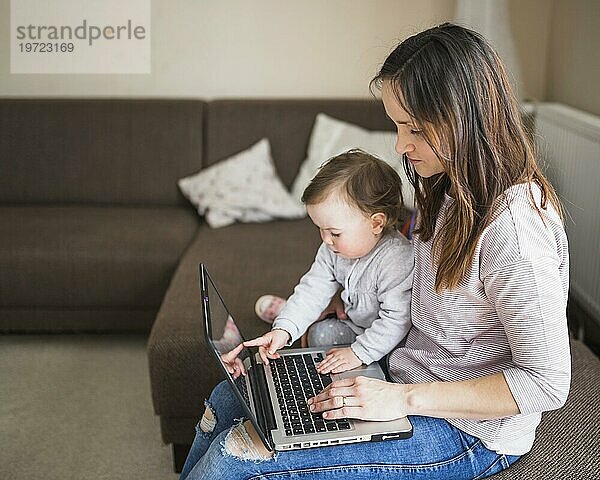 Seitenansicht Mutter mit ihrem Kind auf dem Sofa sitzend mit Laptop