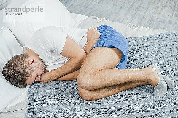 Draufsicht Mann liegend Bett mit Bauchschmerzen