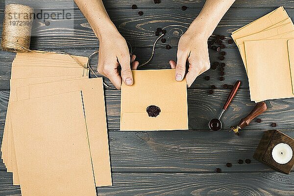 Hohen Winkel Ansicht Frau zeigt Dichtung braunen Umschlag mit Handwerk Material Holztisch