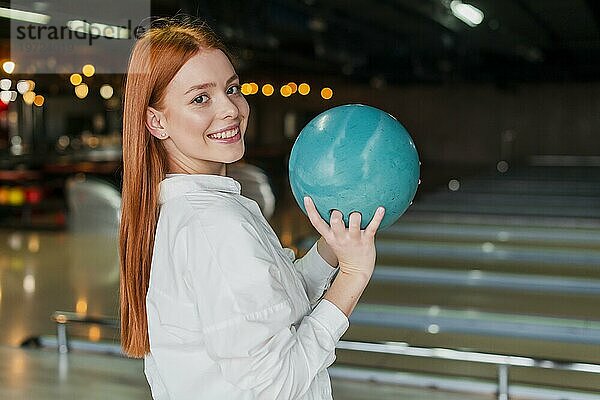Glückliche Frau hält Bowlingkugel