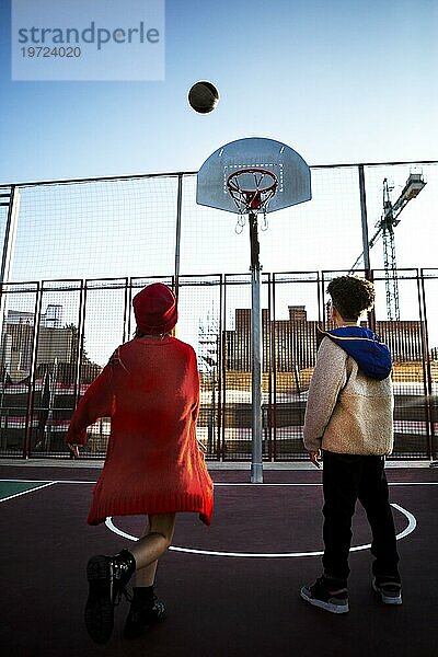 Rückansicht Kinder  die gemeinsam im Freien Basketball spielen