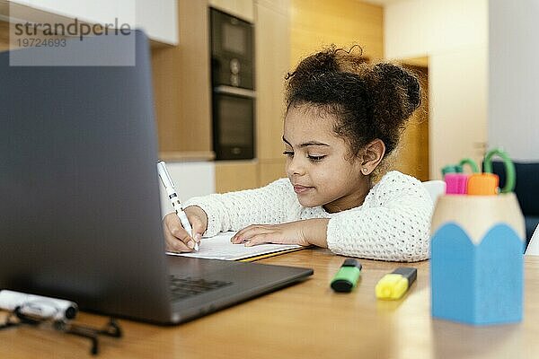 Kleines Mädchen lernt zu Hause in der Onlineschule mit Laptop