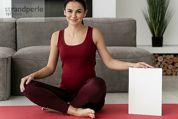 Schwangere Frau posiert weiße Karte