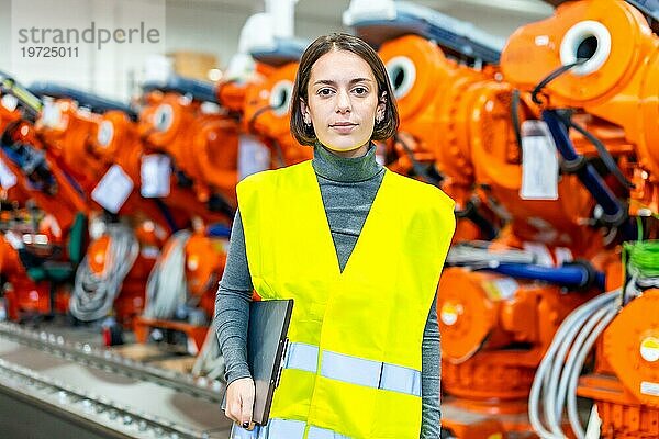 Porträt einer Ingenieurin in einer Fabrik für Roboterarme  die in die Kamera schaut