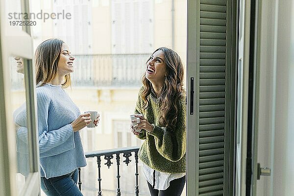 Fröhliche Frauen mit Tassen Balkon