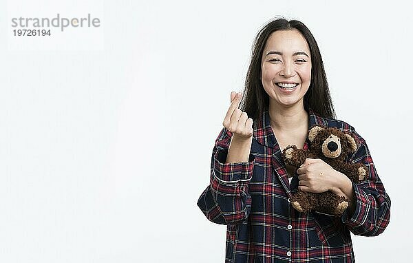 Glückliche Frau mit Teddybär und Herzzeichen