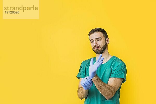 Männlicher Arzt  der sterile Handschuhe anzieht