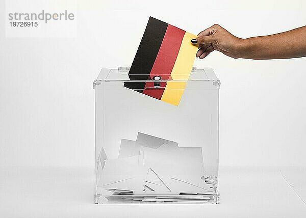Person wirft Deutschlandflagge Karte in Wahlurne