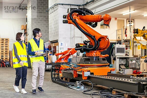 Zwei multiethnische Ingenieure betreten die Fabrik zur Herstellung von Roboterarmen