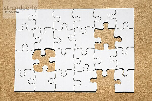 Weißes Puzzlegitter mit fehlendem Puzzlestück braunes Papier strukturiert