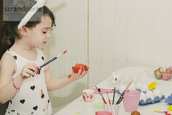 Nettes Mädchen malt Ei mit Rot
