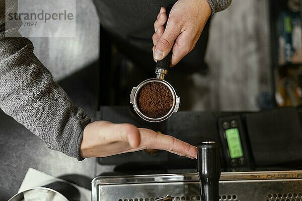 Draufsicht eines männlichen Barista  der eine Tasse einer professionellen Kaffeemaschine hält