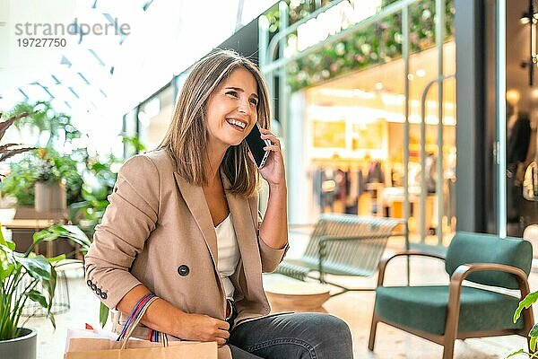 Telefonierende Frau in einem Kaufhaus mit Einkaufstaschen