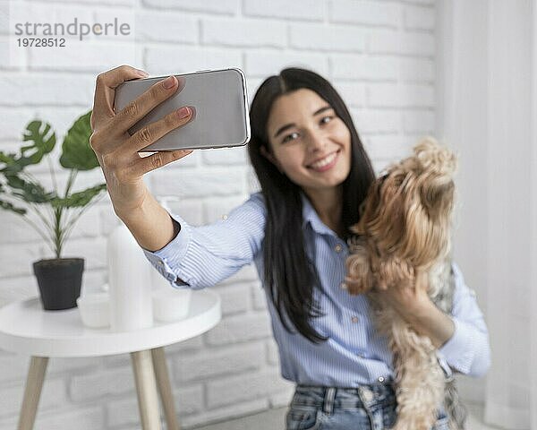 Vloggerin zu Hause mit Smartphone Hund