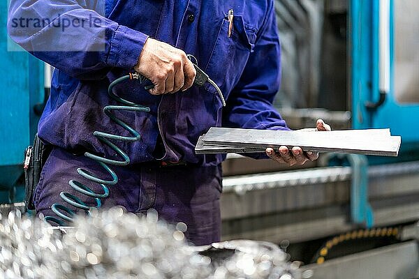 Fabrikarbeiter im Bereich der numerischen Steuerung  der ein Teil mit Druckluft reinigt  Metallindustriewerk