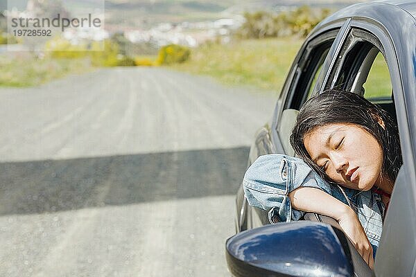 Asiatische Frau  die während eines Roadtrips im Auto ein Nickerchen macht