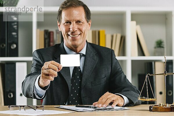 Lächelnd reifen Anwalt zeigt leere Visitenkarte sitzen Gerichtssaal