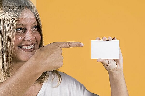 Lächelnde behinderte junge Frau  die auf eine leere Visitenkarte zeigt