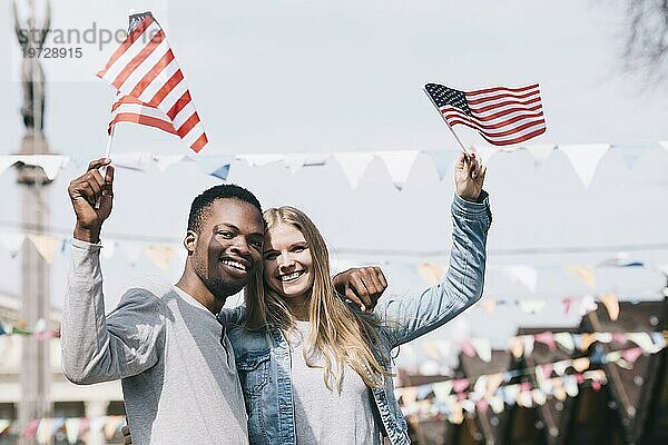 Multiethnische Freunde halten mit ausgestreckten Händen amerikanische Flaggen