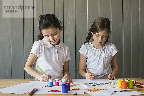 Porträt zwei Mädchen malen weißes Papier Schreibtisch