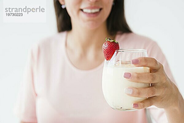 Close up lächelnde junge Frau hält Joghurt Glas mit Erdbeere