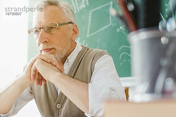Konzentrierter alter Professor  der wegschaut  Klassenzimmer