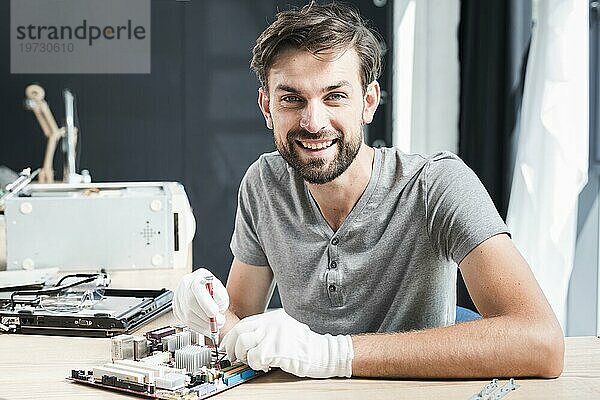 Porträt glücklicher Mann bei der Reparatur einer Computerplatine
