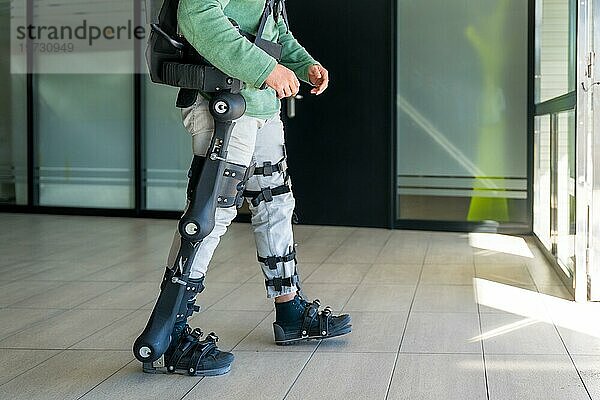 Mechanisches Exoskelett  behinderte Person  die mit Hilfe eines Roboterskeletts geht  Physiotherapie in einem modernen Krankenhaus  futuristische Physiotherapie