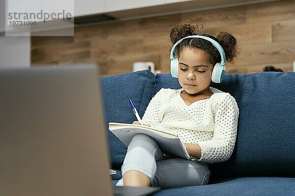 Frontansicht kleines Mädchen in der Onlineschule mit Laptop und Kopfhörern