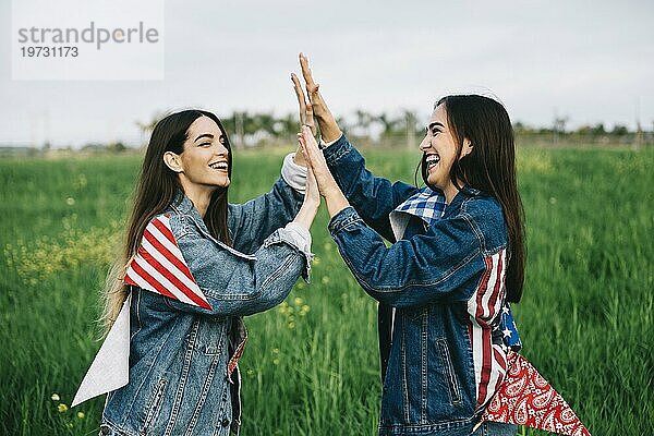 Weibliche Freunde lachen Gras mit amerikanischen Attributen