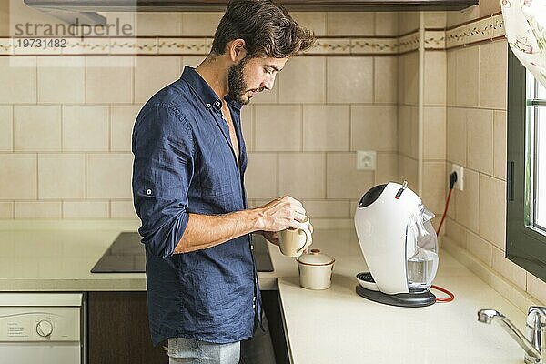 Seitenansicht Mann stehend Küche hält Kaffeebecher