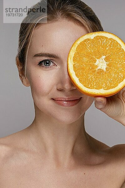 Schöne Frau hält halbierte Orange 2