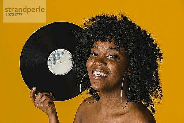 Glückliche junge ethnische Frau hält Vinyl Platte hellen Hintergrund