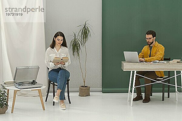 Frau entspannt sich beim Lesen eines Buches  Mann arbeitet am Laptop