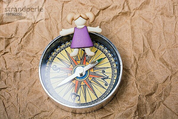 Miniatur Mädchen auf einem Kompass als Bildungs und Geschäftskonzept