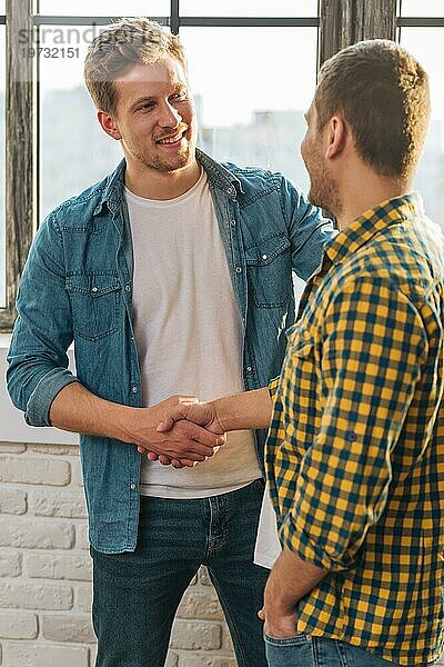 Lächelndes Porträt eines jungen Mannes beim Händeschütteln