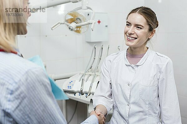 Porträt eines Zahnarztes  der einem Patienten die Hand schüttelt